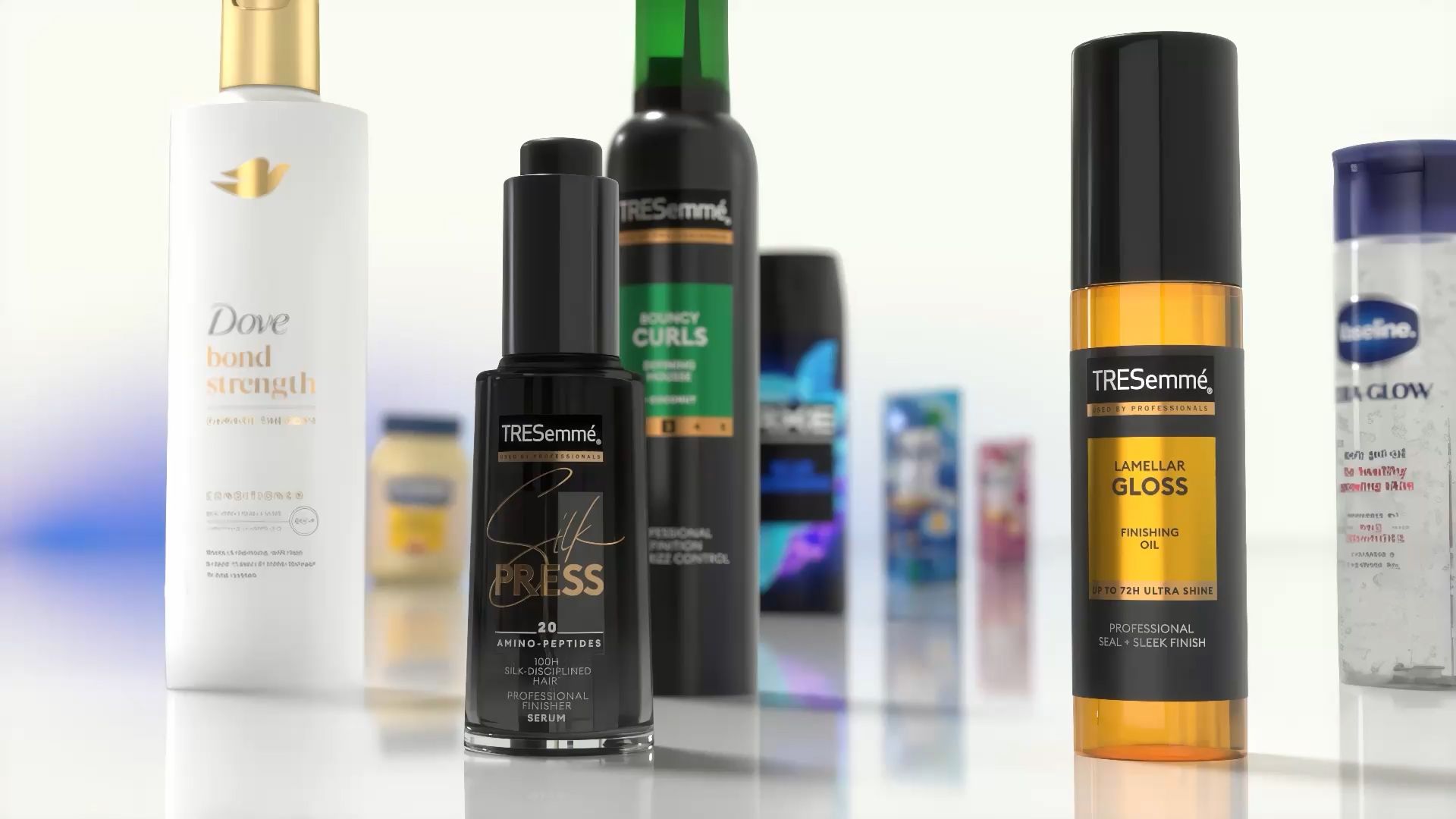 Zbliżenie na różnorodne produkty do pielęgnacji włosów i ciała wyeksponowane na odblaskowej powierzchni. Widoczne produkty to m.in. odżywka Dove Bond Strength, serum TRESemmé Silk Press, olejek wykończeniowy TRESemmé Lamellar Gloss i inne produkty Unilever w tle.
